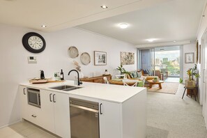 A modern kitchen with a central island, a dining area with a view, and a living room with a sofa and coffee table. - Tropical City Escape (Brisbane)
