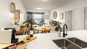 A modern kitchen with a large island, a dining area with a view, and a balcony with a cityscape.