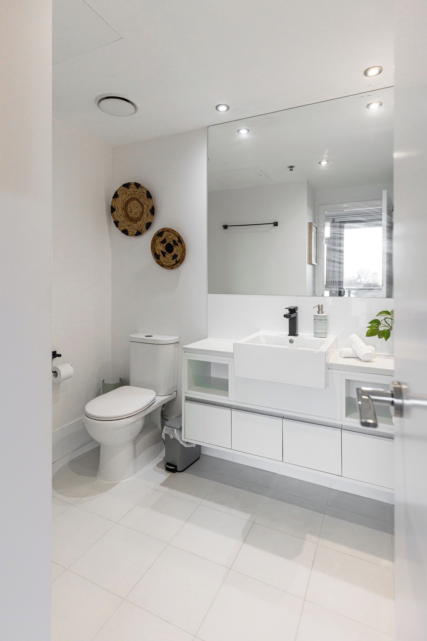 A modern bathroom with a toilet, bidet, and a large mirror above the sink.