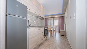 A modern kitchen with a built-in oven, a refrigerator, and a dining area with a table and chairs.