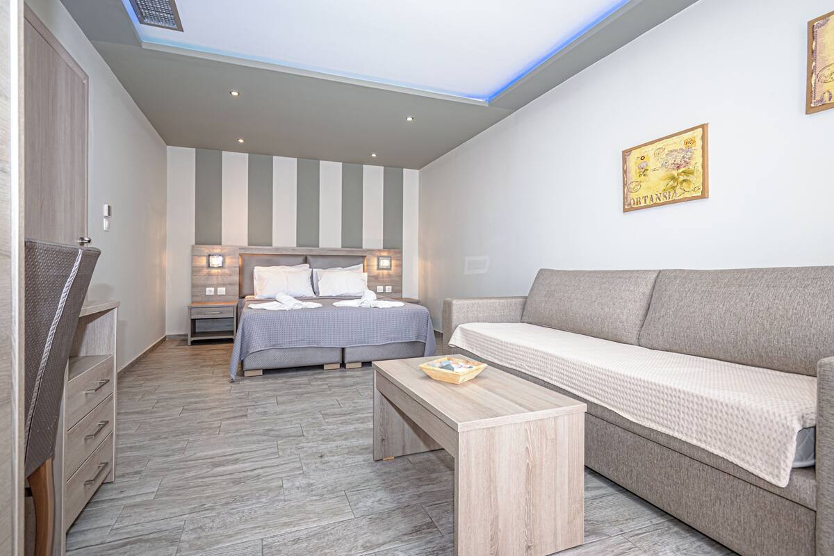 Una habitación de hotel moderna con cama, sofá y una pequeña mesa.