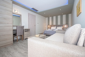 Ett modernt hotellrum med en säng, en soffa, ett skrivbord och en stol.