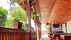 A covered outdoor seating area with wooden benches and hanging plants. - Naparis Boutique  (Eforie Sud)