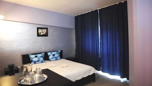 A hotel room with a bed, a bedside table with a tray, a picture on the wall, and a window with dark curtains. - Naparis Boutique  (Eforie Sud)