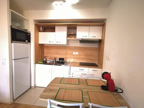Eine kleine Küche mit Mikrowelle, Kühlschrank, Spüle und Holzschränken.