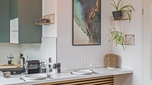 A modern kitchen with a built-in espresso machine, a white countertop, and a large window. - Gleam Homes Dresden HafenCity Urban District (Dresden)