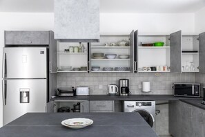 Eine moderne Küche mit integriertem Kühlschrank, Mikrowelle, Toaster, Kaffeemaschine und Geschirrspüler.