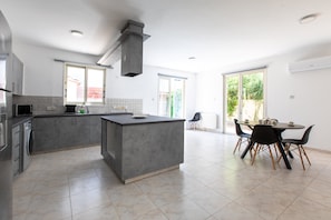 A modern kitchen with a central island, built-in appliances, and a dining area with chairs and a table.