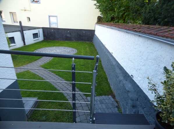 A courtyard with a paved path, a metal railing, and a white building with a door and window. - Newly renovated 84 sqm apartment just 2 minutes from the banks of the Rhine with terrace (Eltville am Rhein)