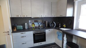 Una cucina moderna con mobili bianchi, forno nero e lavello in acciaio inossidabile.