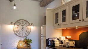 Une cuisine avec des meubles blancs, une horloge et une machine à café.