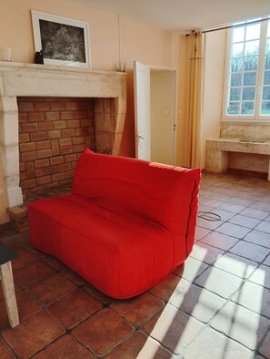 A room with a red sofa, a fireplace, a window, and a door. - Charming House with Garden (La Jemaye-Ponteyraud)
