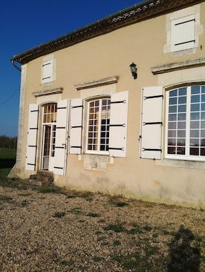 A building with a beige facade, multiple windows with shutters, and a small entrance with steps. - Charming House with Garden (La Jemaye-Ponteyraud)