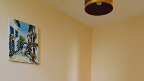 Une chambre avec deux lits, un tableau au mur, une lampe rouge et une chaise en bois.