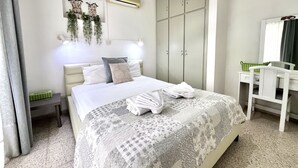 A bedroom with a bed, a wardrobe, a desk, and a hanging plant. - 98 AN - Stay Heaven Apartment (Ayia Napa)