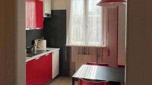 Eine Küche mit roten Schränken, einer schwarzen Arbeitsplatte und einem Essbereich mit Tisch und Stühlen.