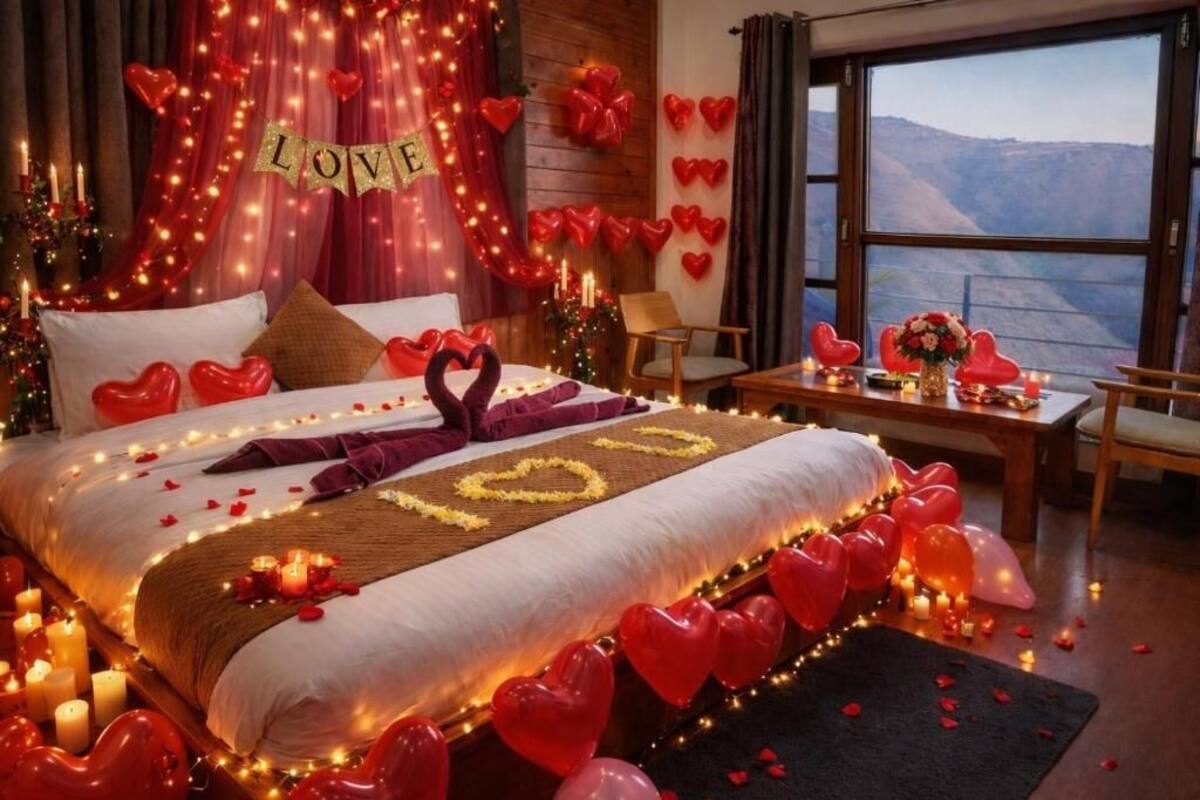 A romantic room with a bed, heart-shaped decorations, candles, and a view of the mountains.