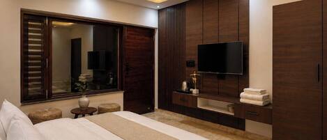 Une chambre à coucher comprenant un lit, un ventilateur de plafond, une télévision, une armoire en bois et un miroir.