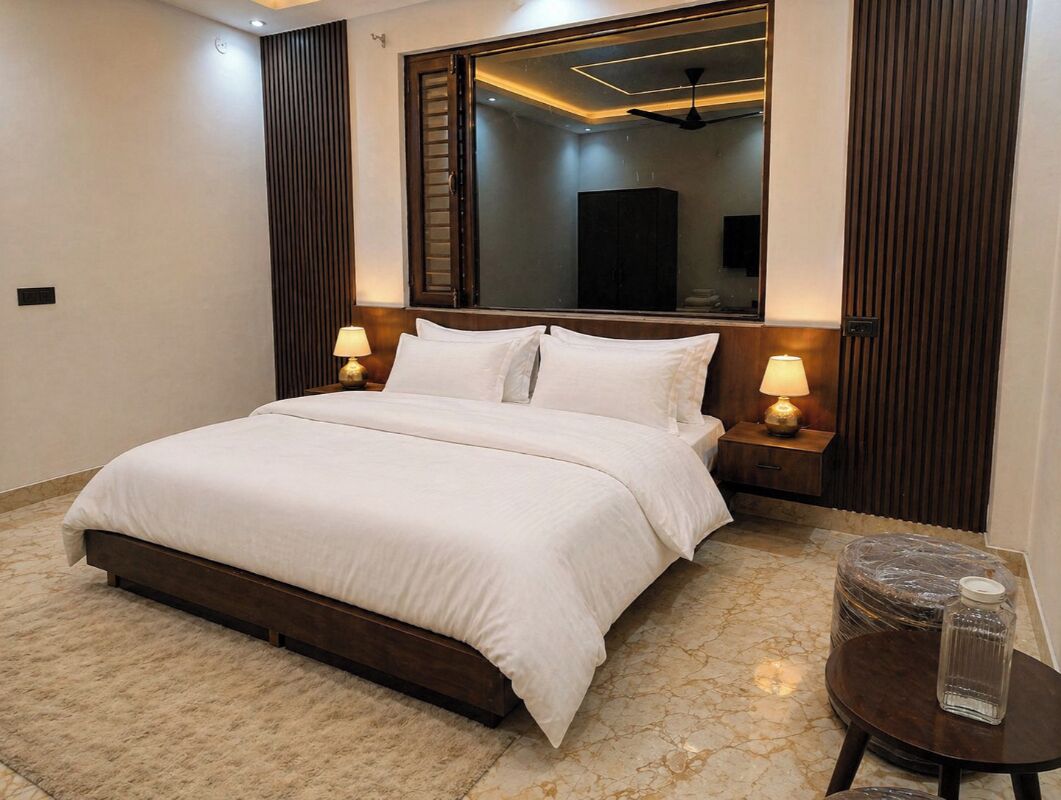 A hotel room with a large bed, two bedside tables with lamps, a mirror above the bed, and a ceiling fan.