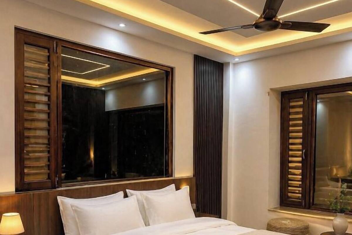 A modern hotel room with a large bed, a ceiling fan, and a nightstand with a lamp.