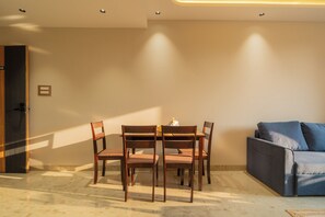A dining area with a table and chairs, a sofa, and a door. - ELIVAAS Kamerios Maris 1 BHK Apartment  (Marra)