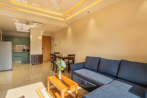 A modern living room with a sofa, a wooden coffee table, and a dining area with a table and chairs. - ELIVAAS Kamerios Maris 1 BHK Apartment  (Marra)