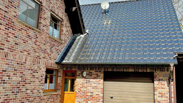 A brick building with a garage, a satellite dish, and a clear sky. - Cozy vacation apartment Vechteglück (Emlichheim)