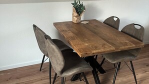 A dining table with four chairs, a potted plant, and a wooden floor. - Cozy vacation apartment Vechteglück (Emlichheim)