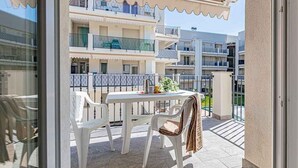 Ein Balkon mit Tisch und Stühlen, Blick auf mehrstöckige Gebäude und einen klaren Himmel.