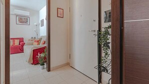 Ein Zimmer mit einem Bett, einem Stuhl, einer Pflanze und einer Tür.