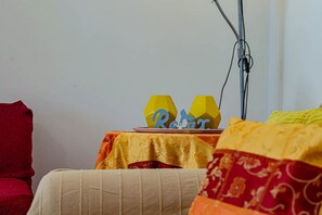 A room with a table covered by a yellow tablecloth, a red chair, and a white couch. - Homiday - Terry's, Two Bedroom Apartment with Balcony (Tortoreto Lido)