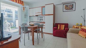 Ein kompakter Wohnbereich mit Essplatz, Küchenzeile und einem roten Sofa.