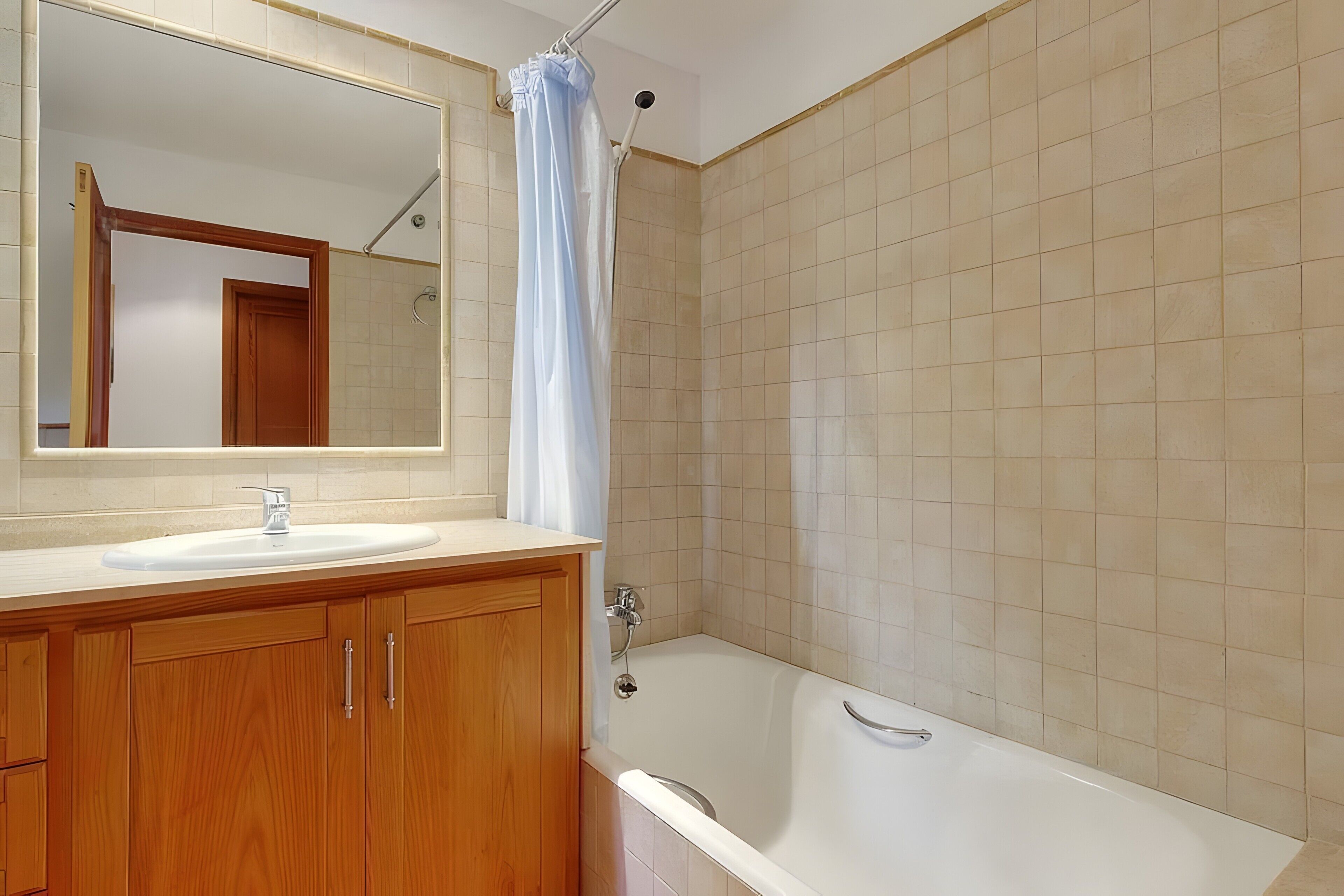 Un baño con bañera, lavamanos y espejo.