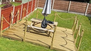 A wooden deck with a picnic table, surrounded by a rope barrier. - Dale Combe, 3 Bedroom House 5 Star on air bnb (Manchester)
