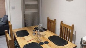 A dining table with a metal rack, black placemats, and a clear glass light fixture above. - Dale Combe, 3 Bedroom House 5 Star on air bnb (Manchester)