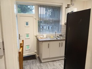 A compact kitchen with a window, a sink, and a refrigerator. - Dale Combe, 3 Bedroom House 5 Star on air bnb (Manchester)