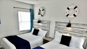 A hotel room with two beds, a window with blinds, a wooden headboard, and two life rings on the wall. - Walk to Beach, Tropical Patio, World Cup, Sleeps 5 (Long Beach)