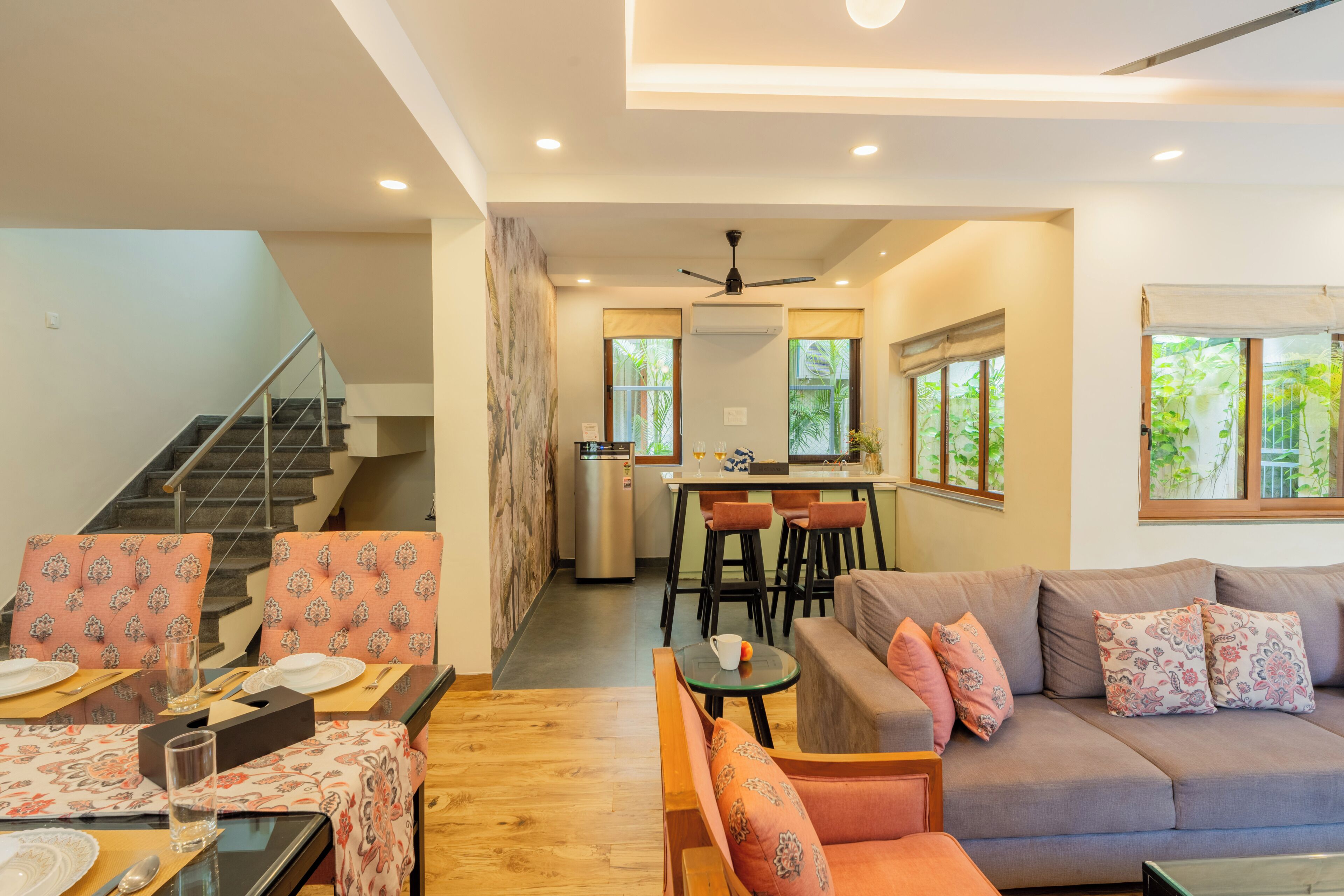 A modern living room with a sofa, chairs, a dining table, and a kitchen area in the background.