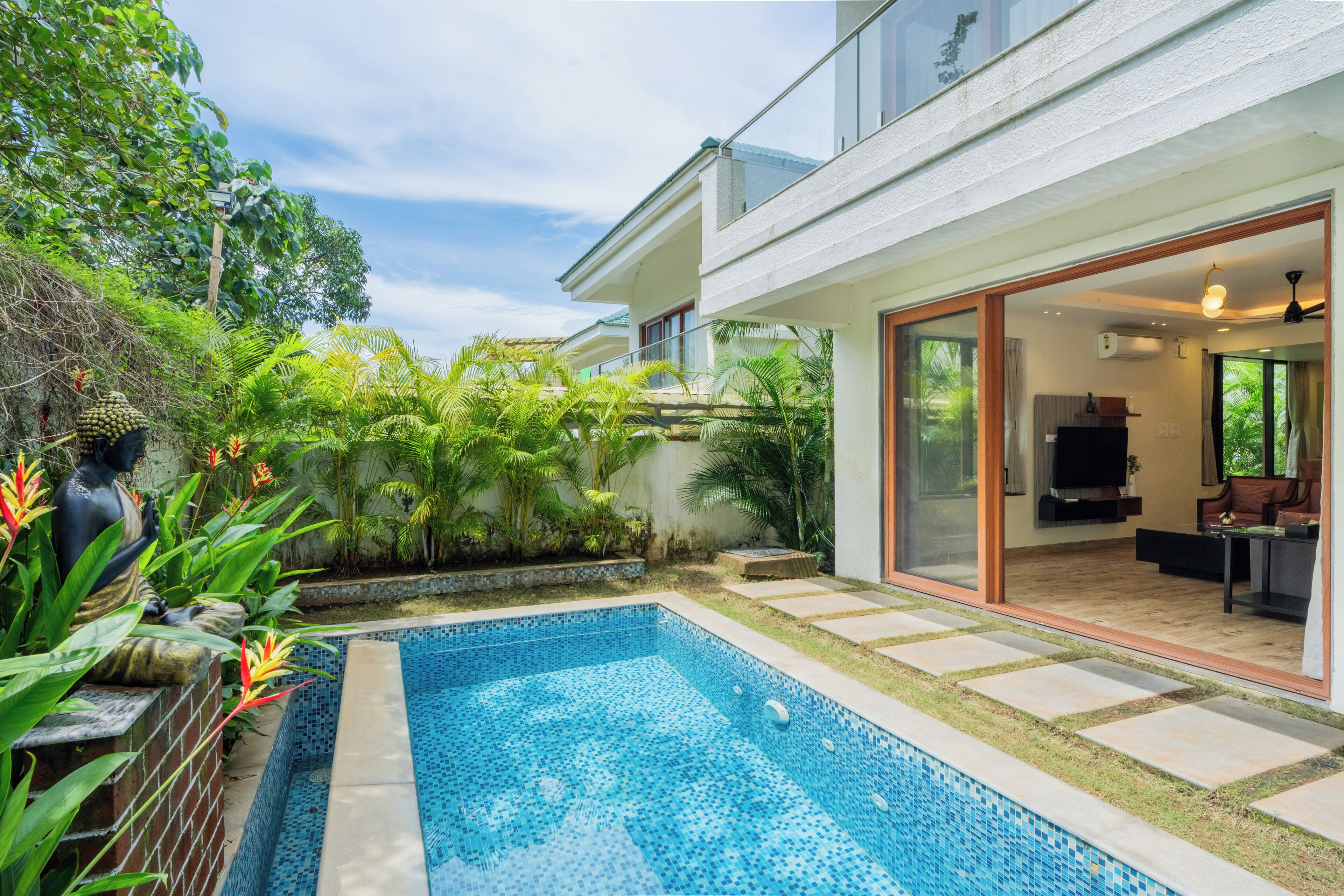 Una casa moderna con piscina, un patio y un amplio ventanal que da a una sala de estar.