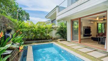 Una casa moderna con piscina, un patio y un amplio ventanal que da a una sala de estar.