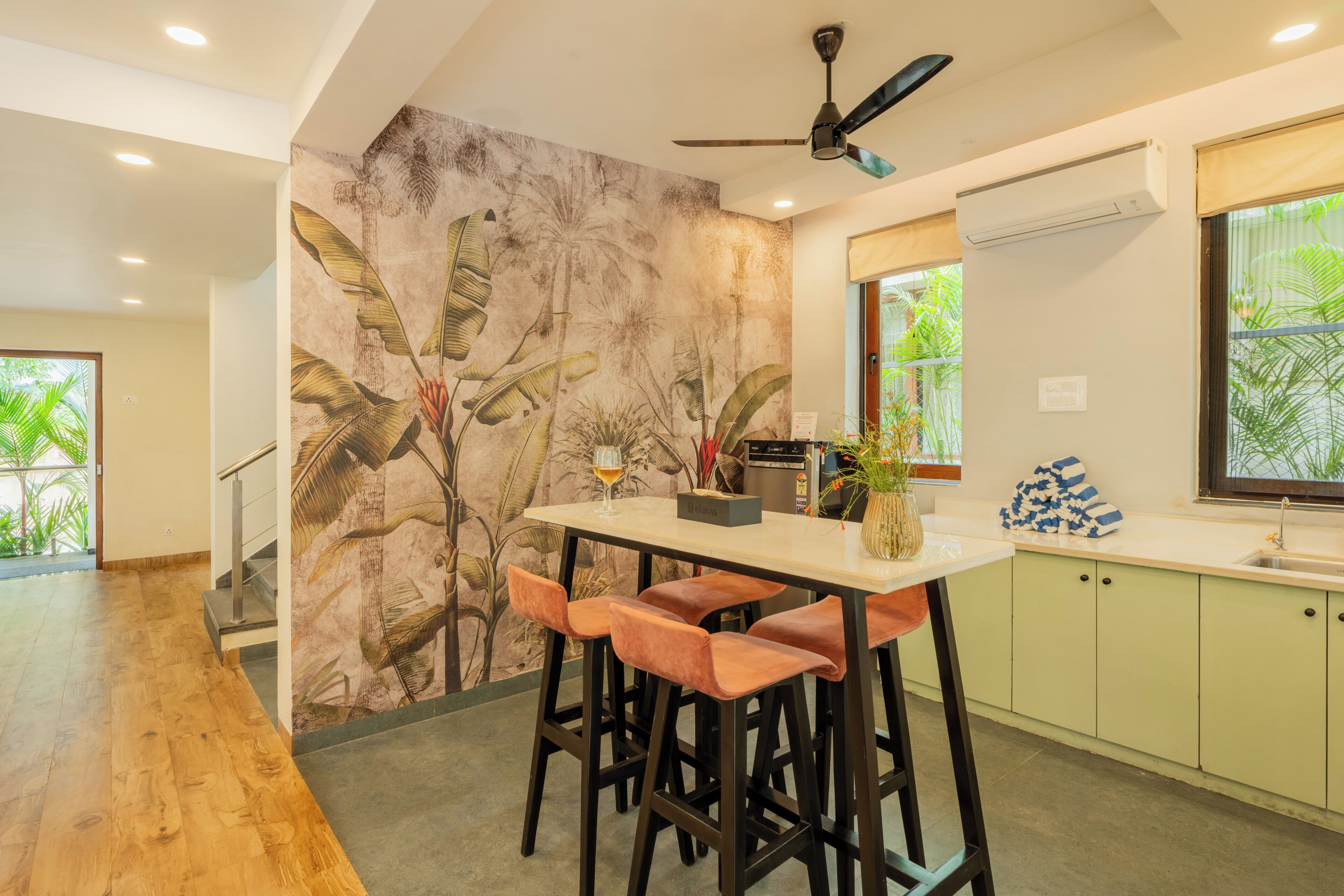 A modern kitchen with a bar area, a ceiling fan, and a tropical mural on the wall.