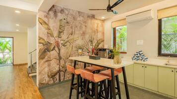 A modern kitchen with a bar area, a ceiling fan, and a tropical mural on the wall.