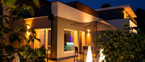 Una casa moderna con un patio, mobiliario exterior y un interior visible.