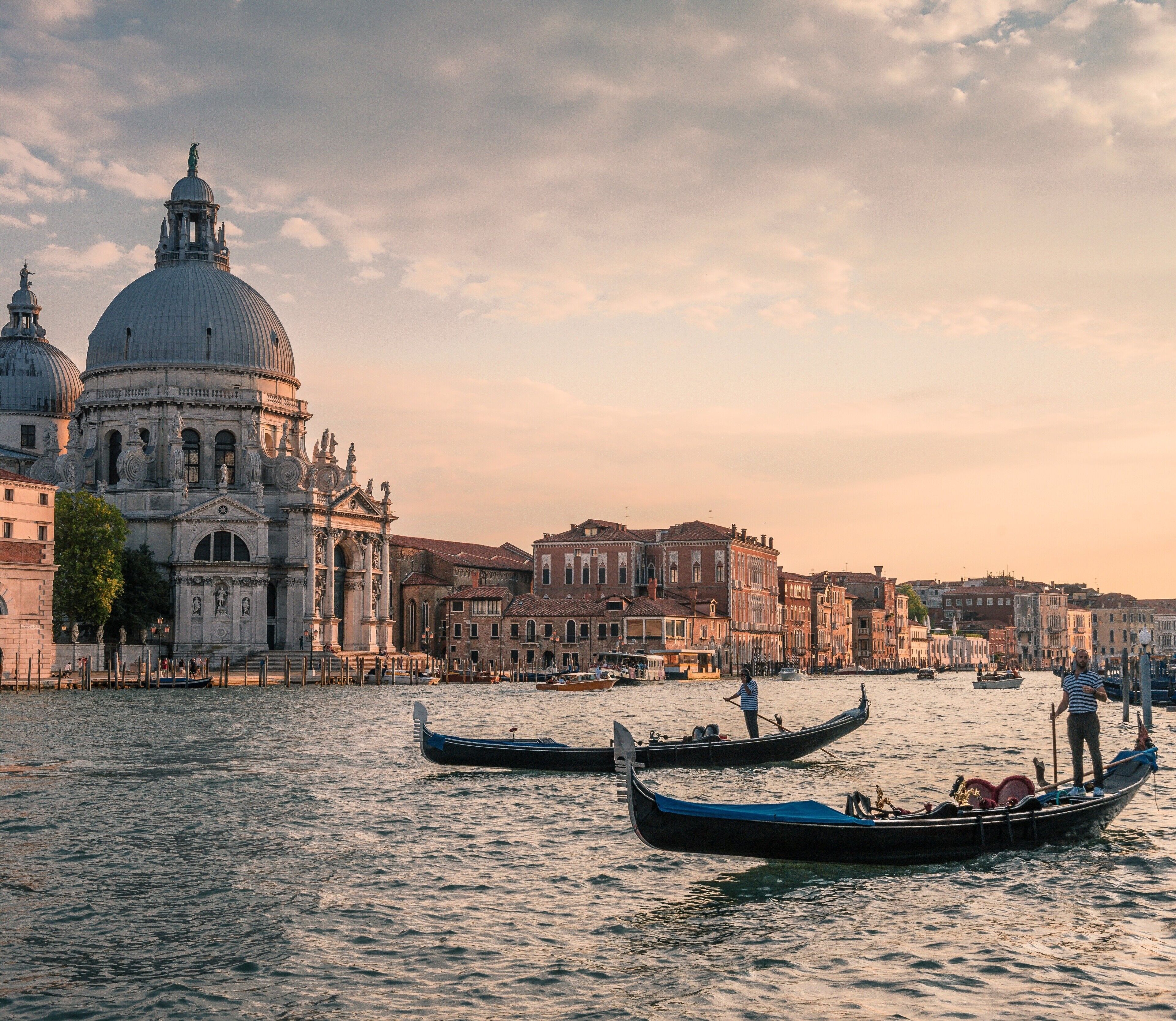 A canal with gondolas, historic buildings, and a large dome structure.