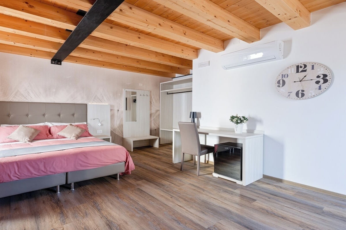 Un dormitorio moderno con cama, mesitas de noche, escritorio y un reloj en la pared.