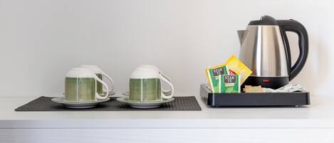 A kitchen counter with two white mugs, a black electric kettle, and a box of tea bags.
