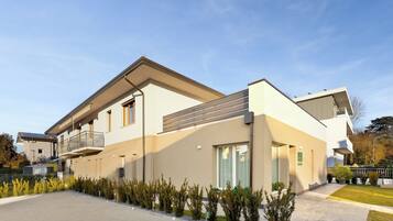 Una casa moderna a due piani con tetto piatto, ampie finestre e una zona esterna coperta.