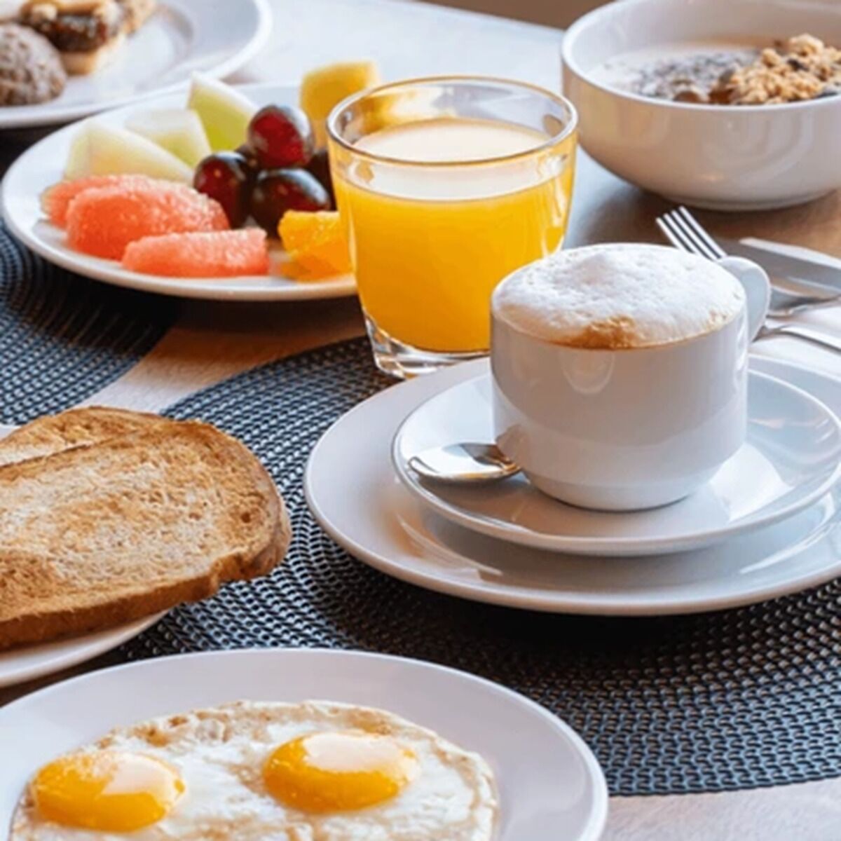 A breakfast setting with toast, eggs, a cup of coffee, and a glass of orange juice.
