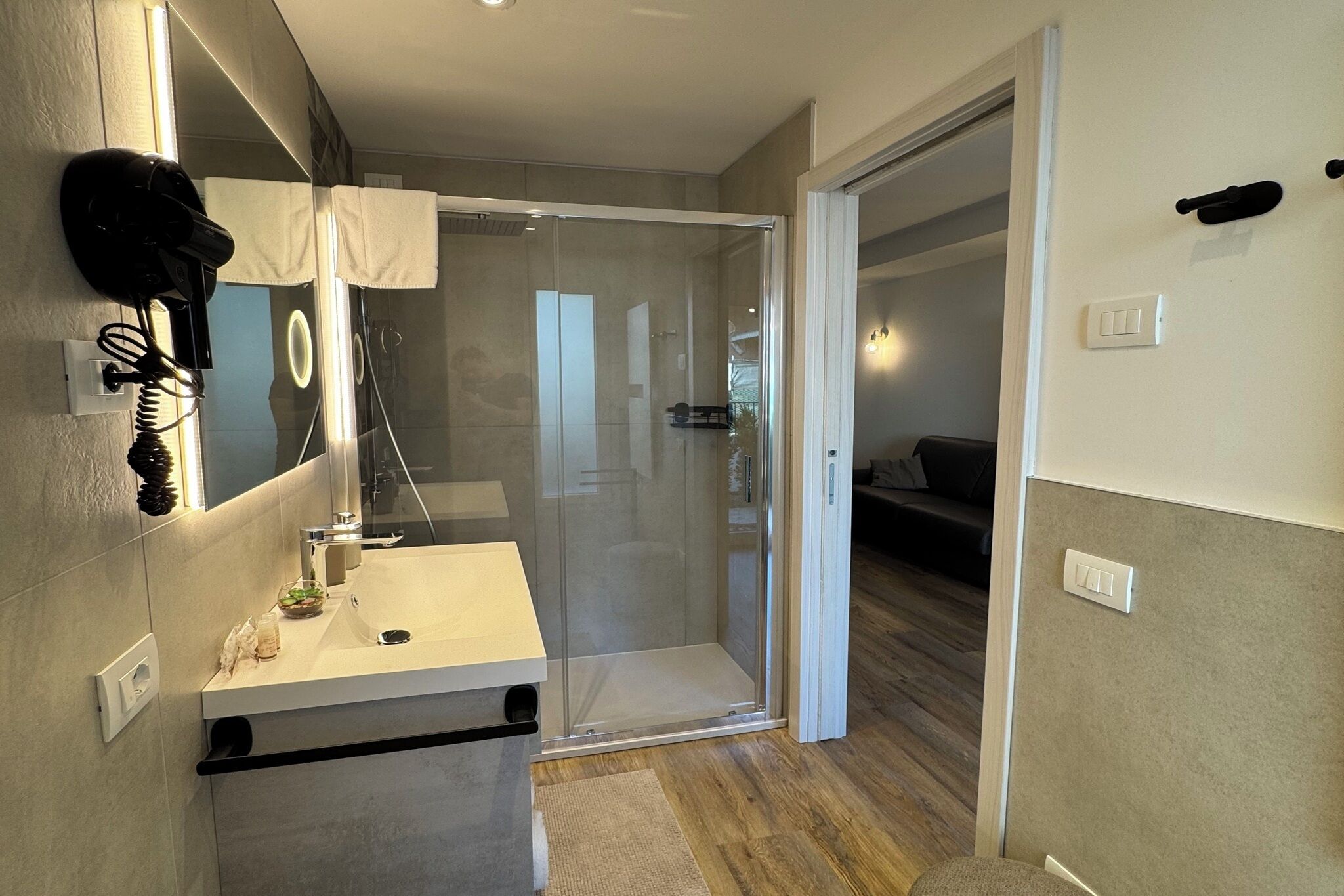 A modern bathroom with a glass shower enclosure, a vanity with a mirror, and a towel rack.