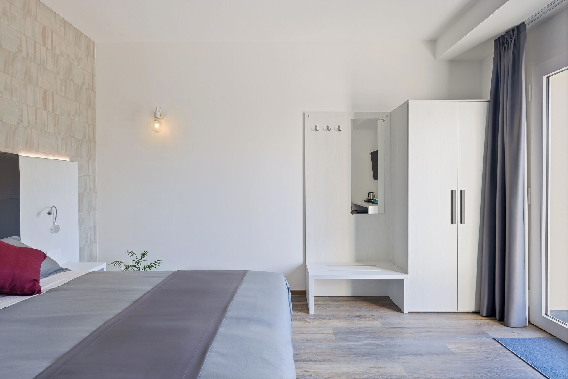 Ein modernes Schlafzimmer mit Bett, Nachttisch, Kleiderschrank und Duschbereich.